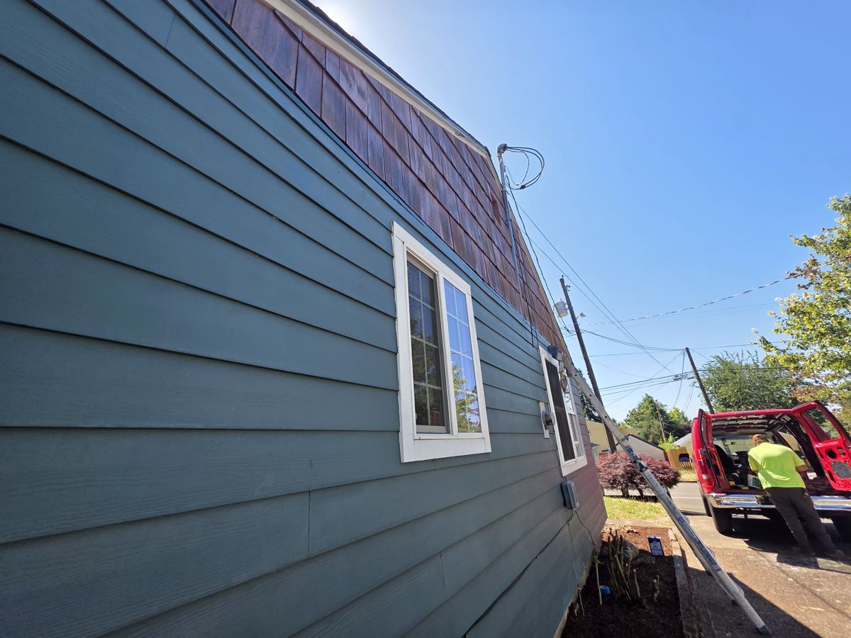 Cedar shingle siding progress over blue lap siding on an Oregon home